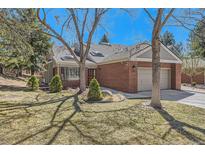 Charming brick home featuring mature trees, a well-manicured lawn, and an attached two-car garage at 8834 Blue Mountain Pl, Highlands Ranch, CO 80126