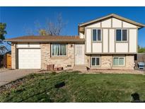Charming two-story home with brick and white siding, a well-maintained lawn, and an attached garage at 1509 S Lewiston St, Aurora, CO 80017