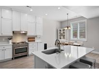Bright kitchen with white cabinets, stainless steel appliances, and an adjacent dining area at 12214 Stone Timber Ct, Parker, CO 80134