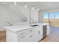Bright white kitchen boasts stainless steel appliances, ample cabinet space, and an island with stone countertops at 10860 Lyric St, Lone Tree, CO 80134