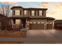 Charming two-story home with stone accents, three-car garage, and manicured front yard at 17077 E 111Th Ave, Commerce City, CO 80022