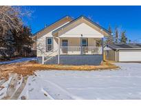 Charming, two-story house with a welcoming front porch and a detached garage with snow covering the ground at 202 Lower Glenway St, Palmer Lake, CO 80133