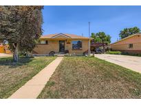 Charming brick home featuring a well-kept front lawn, covered parking, and welcoming curb appeal on a sunny day at 7146 Jennie Dr, Denver, CO 80221