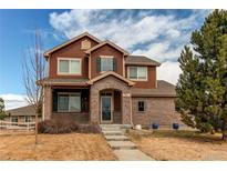 Charming two-story home features a brick-and-wood exterior, manicured front yard, and welcoming entrance at 5540 Palomino Way, Frederick, CO 80504