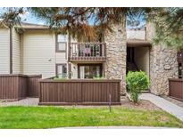 Inviting condo exterior with stone accents, second story balcony, and charming wood fence at 7710 W 87Th Dr # K, Arvada, CO 80005