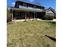 Charming two-story home with a spacious front yard and inviting front porch with rocking chairs at 4196 S Reading Way, Denver, CO 80237
