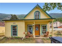 Charming yellow two-story home with a covered porch and mountain views at 400 Argentine St, Georgetown, CO 80444