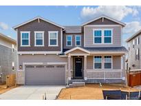 Charming two-story home boasts a covered porch, two-car garage, and attractive mixed-material facade at 25254 E Warren Pl, Aurora, CO 80018