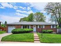 Charming brick home featuring a well-manicured lawn, mature landscaping, and an attached garage at 8490 E Davies Pl, Centennial, CO 80112