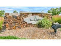 Stone monument sign at Turnberry community entrance with beautiful landscaping and blue skies at 13342 E 110Th Way, Commerce City, CO 80022