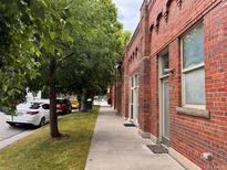 Brick exterior of building with sidewalk and street parking lined by grass and shady trees at 1111 Osage St # 7, Denver, CO 80204