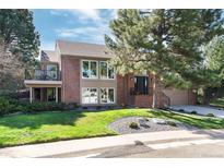 Two-story brick home with a balcony, mature trees, and a well-manicured lawn at 8004 S Oneida Ct, Centennial, CO 80112