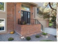 Charming brick front entrance with black door, minimalist railing, and beautiful landscaping detail at 8004 S Oneida Ct, Centennial, CO 80112