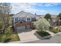 Stunning home exterior with brick accents, three car garage, and a lovely flowering tree at 22090 E Arbor Dr, Aurora, CO 80016