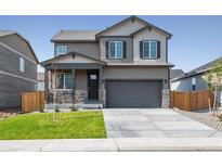 Two-story house with gray siding, stone accents, and a two-car garage at 9876 Ceylon Ct, Commerce City, CO 80022