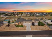Expansive aerial view of a ranch home with manicured landscaping, outbuildings, and fenced yard at sunset at 12590 Valentia St, Thornton, CO 80602