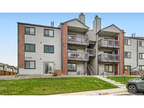 A multi-level condo building featuring grey siding, brick accents, and private balconies on each floor at 10785 W 63Rd Pl # 108, Arvada, CO 80004