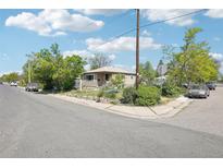 Charming single-story home featuring classic siding and a cozy front porch, surrounded by mature trees on a sunny day at 801 Hanover St, Aurora, CO 80010