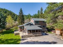 Charming home featuring a stone foundation, screened porch, and surrounded by lush greenery and mature trees at 11531 S Deer Creek Rd, Littleton, CO 80127