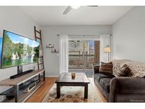 Cozy living room with a dark couch, sliding glass doors to a balcony, and modern decor at 9961 E Idaho Cir # 104, Aurora, CO 80247
