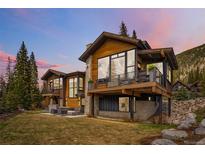 Stunning wood and stone home featuring a patio, expansive windows, and a mountain view at 427 Whispering Pines Cir, Breckenridge, CO 80424