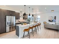 Modern kitchen features stainless steel appliances, a large island with seating, and sleek cabinetry at 10151 W 38Th Ave, Wheat Ridge, CO 80033