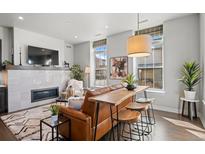 Modern living room showcasing a fireplace, stylish seating, and a unique bar-height table with stools at 4625 W 50Th Ave # 110, Denver, CO 80212