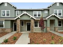 Inviting townhouse with stone accents, covered porch, manicured landscaping, and modern design at 17125 W 91St Ln, Arvada, CO 80007