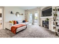 Living room with fireplace and sliding glass door to deck on a bright sunny day at 5255 Memphis St # 311, Denver, CO 80239