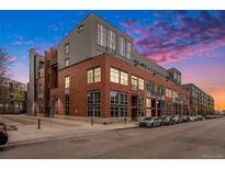 Modern building with red brick and large windows, complemented by a colorful sunset at 2955 Inca St # 2L, Denver, CO 80202