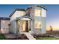 Charming two-story home featuring stone accents, light green siding, and an inviting red front door at 21104 E 63Rd Dr, Aurora, CO 80019