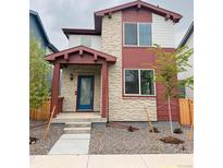 Inviting two-story home with stone accents, covered porch, and a blue front door at 21104 E 63Rd Dr, Aurora, CO 80019