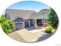 Charming blue home with a well-manicured front yard and covered front porch, plus attached two-car garage at 5309 W Hoover Dr, Littleton, CO 80123