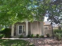 Charming single-story home featuring a welcoming front porch, stone accents, and mature trees at 601 Clarendon Loop, Castle Pines, CO 80108