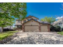 Charming two-story home featuring a three car garage and inviting front porch, framed by mature trees and a landscaped yard at 18885 E Union Dr, Aurora, CO 80015