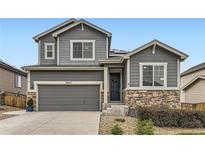 Charming two-story home showcasing a gray facade, stone accents, and a well-manicured front yard at 7833 Bandit Dr, Castle Rock, CO 80108