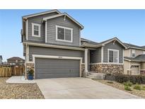 Charming two-story home with a gray exterior, stone accents, well-maintained landscaping, and a two-car garage at 7833 Bandit Dr, Castle Rock, CO 80108