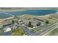 An aerial view of a brick building near a picturesque lake on a sunny day at 5425 County Road 32 # 14, Mead, CO 80504