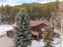 Mountain home featuring a large yard, balcony, and a two-car garage nestled amongst mature trees in a picturesque mountain landscape at 9239 Black Mountain Dr, Conifer, CO 80433