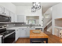 Bright kitchen features white cabinets, stainless steel appliances, tile backsplash, and center island at 12753 Buckhorn Creek St, Parker, CO 80134