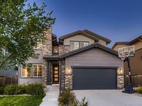 Charming two-story home with a stone facade, gray siding, and a basketball hoop on the driveway at 10968 Pastel Pt, Parker, CO 80134