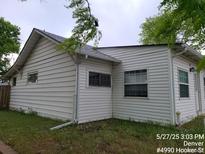 White house with windows and a nice yard surrounded by trees at 4990 Hooker St, Denver, CO 80221