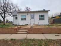Charming single-story home featuring a well-manicured lawn and a welcoming front porch at 4990 Hooker St, Denver, CO 80221