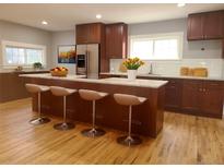 Modern kitchen boasts stainless steel appliances, a center island with seating, and wood floors at 4990 Hooker St, Denver, CO 80221