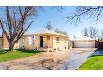 Charming yellow brick home with a well-manicured lawn, an American flag, and a detached two-car garage at 2548 S Zurich Ct, Denver, CO 80219