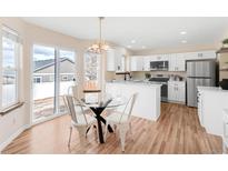 Eat-in kitchen with bright white cabinets, stainless appliances, and sliding glass door to the back yard at 205 Hawthorn St, Frederick, CO 80530