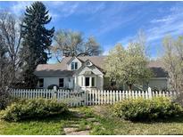 Charming home with a white picket fence and blossoming trees under a sunny sky at 6375 E 6Th Avenue Pkwy, Denver, CO 80220
