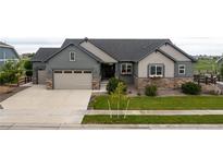 Charming home featuring a two-car garage, stone accents, a well-manicured lawn, and tasteful landscaping at 11259 Kalispell St, Commerce City, CO 80022