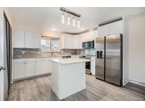 Bright kitchen with gray floors, white cabinets, stainless steel refrigerator, and stone countertops at 1832 Simms St, Lakewood, CO 80215