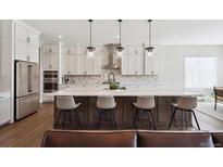 Bright modern kitchen with quartz counters, stainless steel appliances, an island with seating, and pendant lighting at 7334 Canyonpoint Rd, Castle Pines, CO 80108